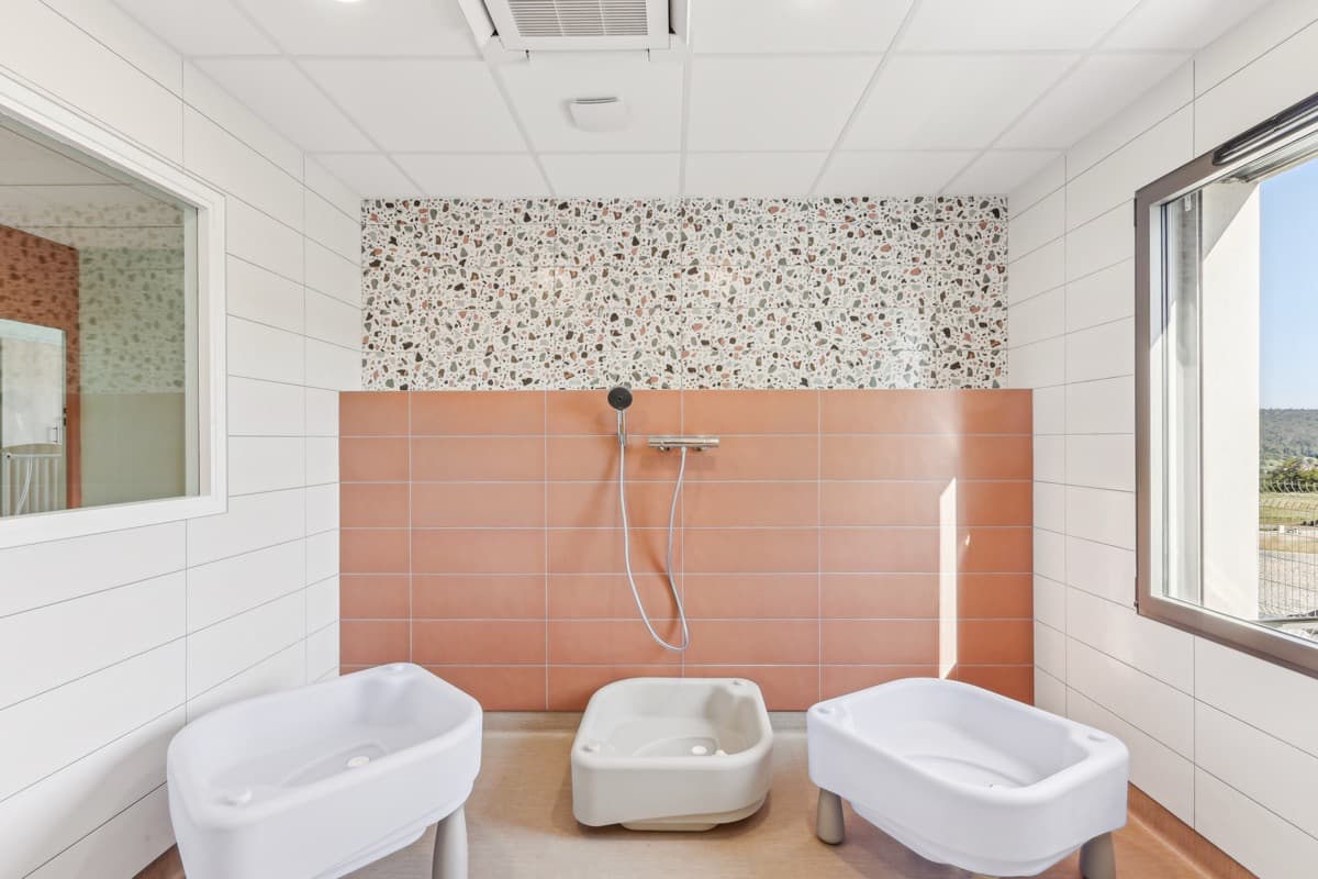 Salle de jeux d'eau avec baignoires adaptées et carrelage terrazzo